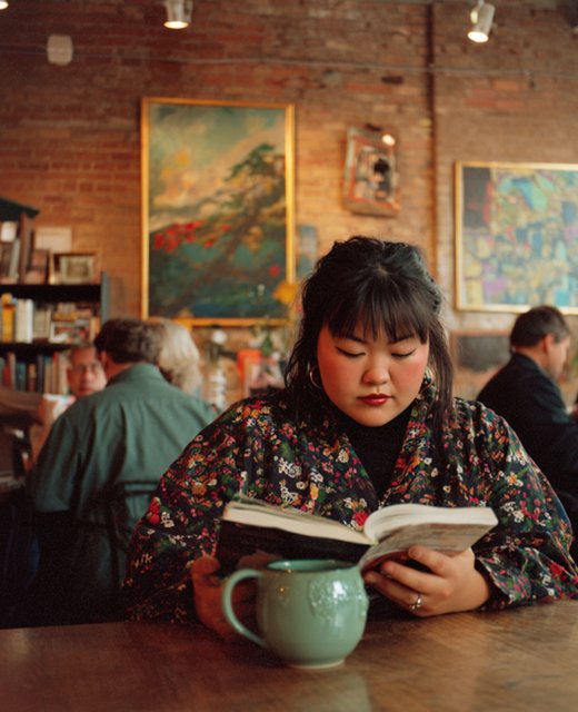 Woman reading in a warm café with a green ceramic mug